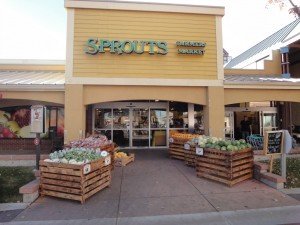 Boulder Sprouts Farmer Market Vegatables in bins lining the walkway leading to a sunny Boulder Sprouts Farmer Market
