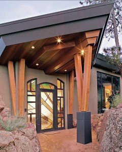 The grand front entyway to a mountain home, with colorful leaded glass doorway and overhanging archway entry