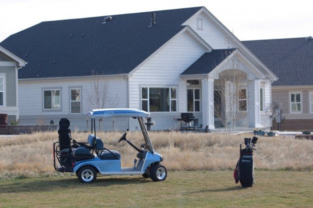 golf cart on golf couse in front of a house